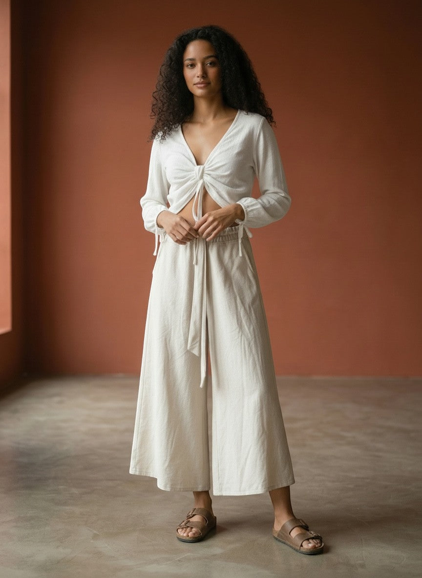 Blusa cropped branca Goa Nomads com decote V e amarração frontal, mangas longas e elástico na cintura.