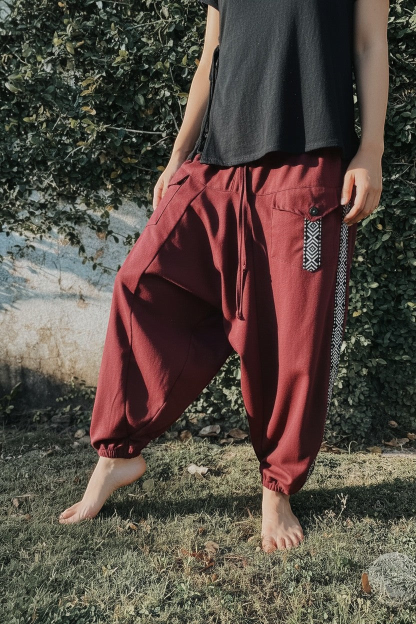 Goa Nomads burgundy linen Aladdin pants with ethnic side trim and asymmetric pockets, cuffed ankles.