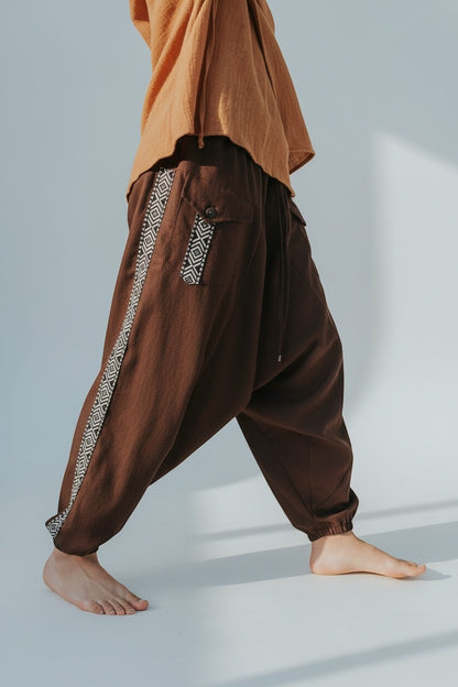 Calça Aladim Goa Nomads em linho marrom com fita étnica lateral e bolsos assimétricos.