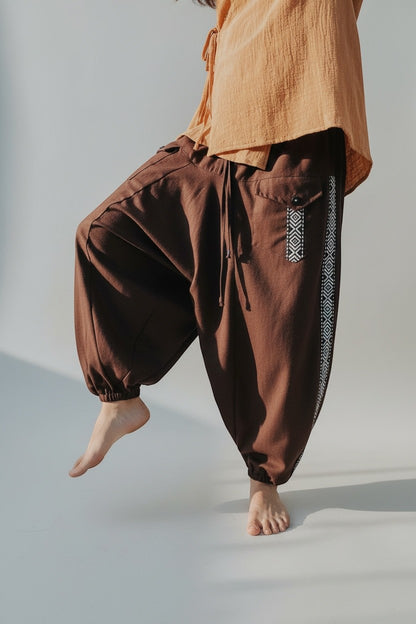 Calça Aladim Goa Nomads em linho marrom com fita étnica lateral e bolsos assimétricos.