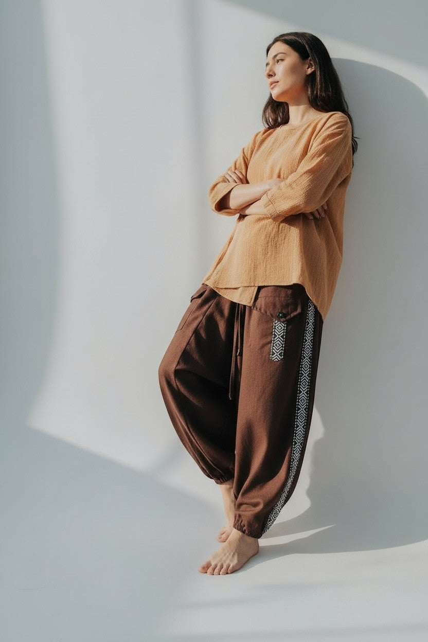 Calça Aladim Goa Nomads em linho marrom com fita étnica lateral e bolsos assimétricos.