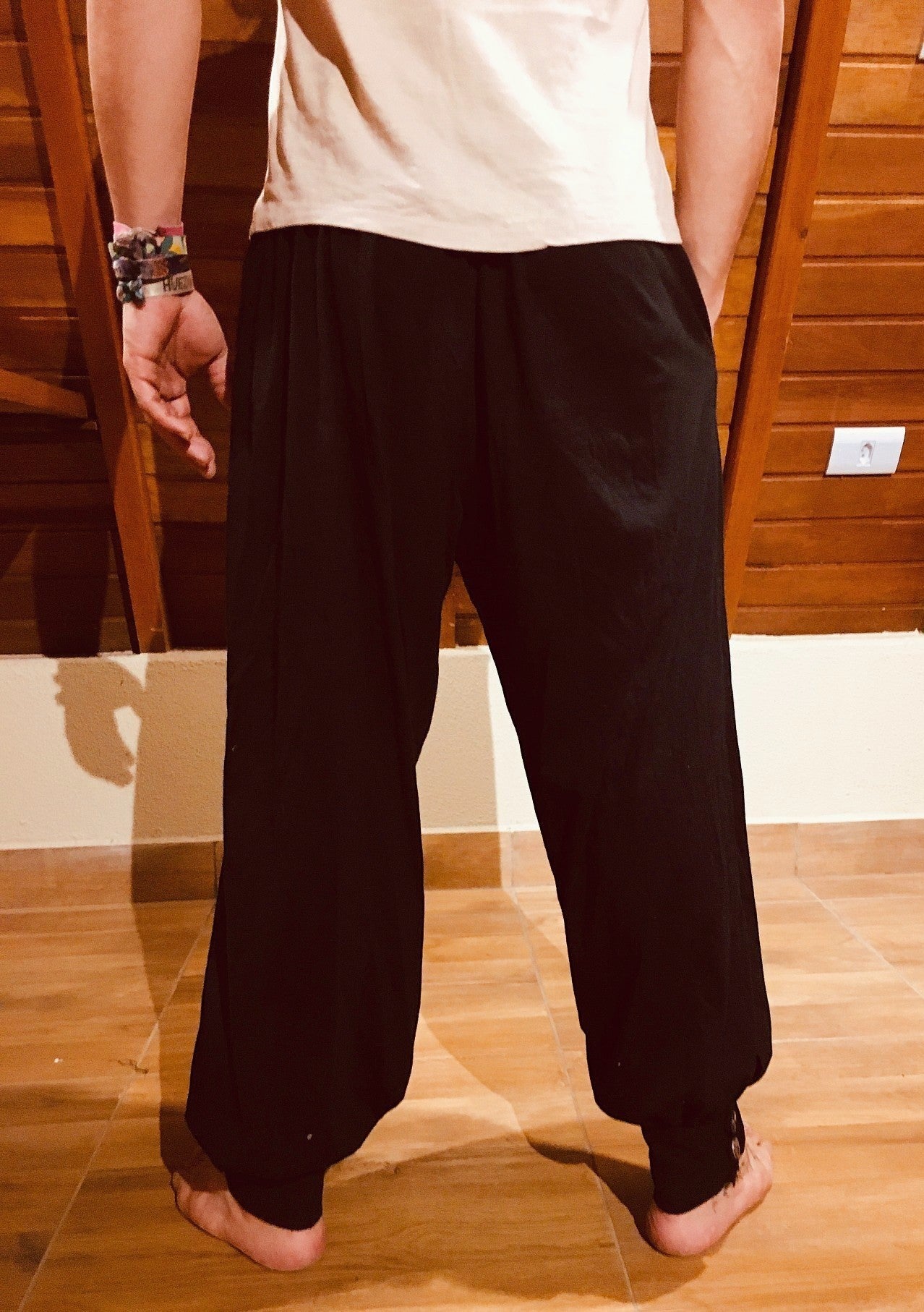 Calça hindu preta em malha ecológica Goa Nomads, com elástico na cintura, bolsos e botões de coco natural nos tornozelos.