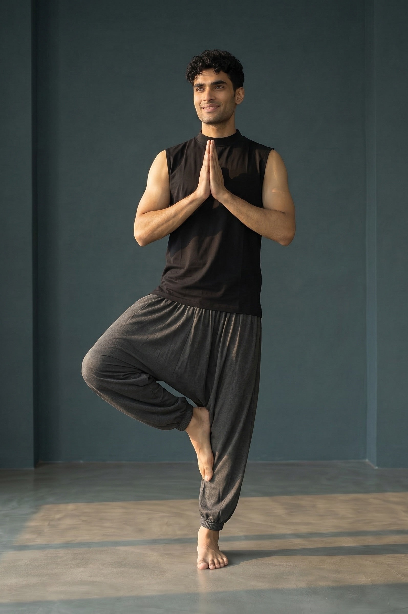 Calça Thai chumbo em algodão penteado, com modelagem solta e elástico na barra, usada por homem em pose de yoga.