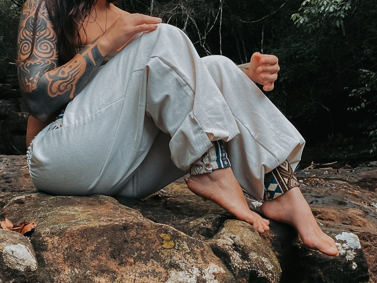 Goa Nomads light beige linen blend pants with embroidered cuffs in blue and brown geometric pattern.