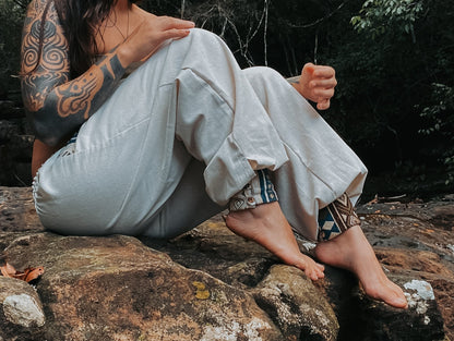 Goa Nomads light beige linen blend pants with embroidered cuffs in blue and brown geometric pattern.